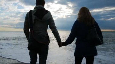 Bir adam ve deniz arka planı ellerini tutan bir kadın silüeti