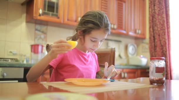 Meisje pizza en spelen met de telefoon in de keuken aan tafel fruit eten — Stockvideo