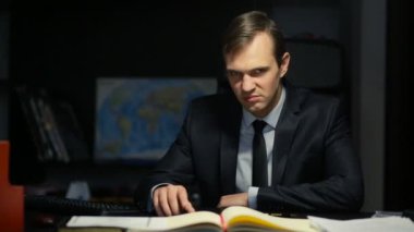 Kötü iş adamı, resmi, tehditkar bir şekilde ofis masasında otururken kameraya bakıyor