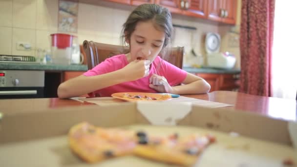 Menina comendo pizza e frutas brincando com telefone na cozinha à mesa — Vídeo de Stock