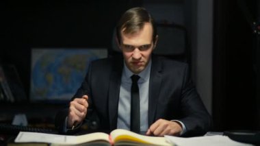 Kötü iş adamı, resmi, tehditkar bir şekilde ofis masasında otururken kameraya bakıyor