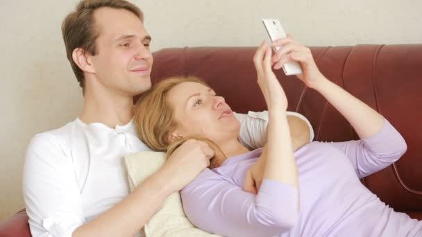 Jeune couple se détendre sur le canapé dans le salon, embrasser doucement et parler — Video