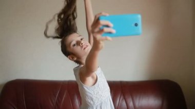 Küçük kız selfie smartphone cep telefonu ile evde kanepede yapıyor