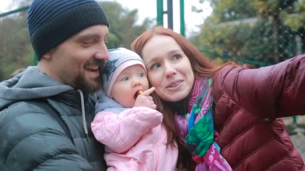 Mamma e papà, giocando con il loro bambino, seduti in un passeggino: passeggiare nel parco — Video Stock