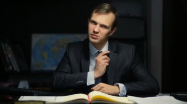 Seksi iş adamı, resmi, baştan çıkarmayı kameraya doğru görünüyor. Ofiste masasında oturuyor. Müstehcen hareketler