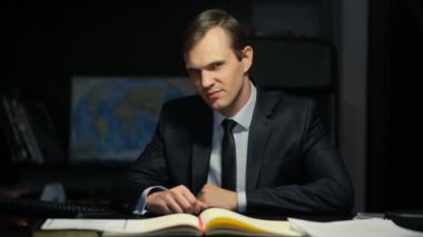 Tehditkar bir şekilde kameraya bakarak bir kızgın iş adamı, devlet memuru. ofiste masasında oturuyor. Uygunsuz hareketleri