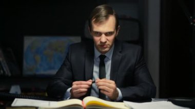 Kötü iş adamı, resmi, tehditkar bir şekilde ofis masasında otururken kameraya bakıyor