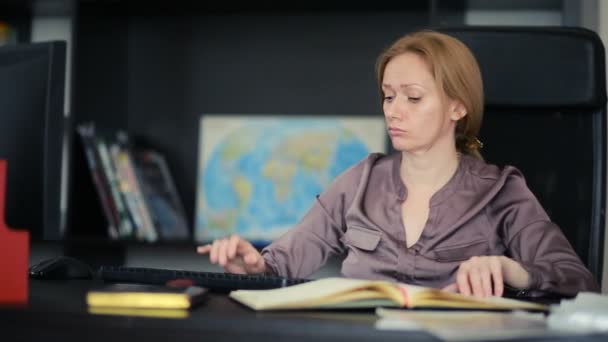 Attraktiva kvinna som arbetar med en dator och dokument i office — Stockvideo