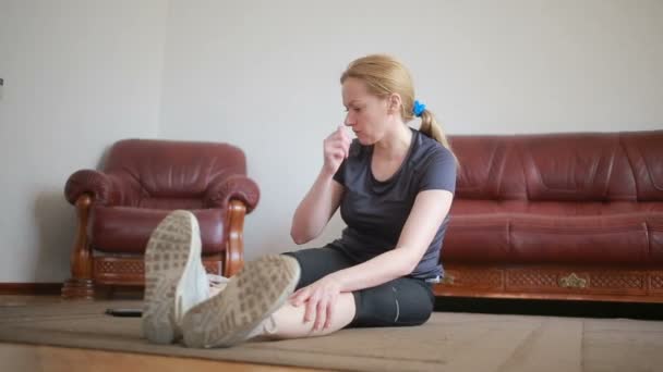 Een huisvrouw vrouw doet fitness oefeningen voor de eerste keer, het Tablet PC en de Tv kijken, is het moeilijk en onbekend, ze is moe. — Stockvideo