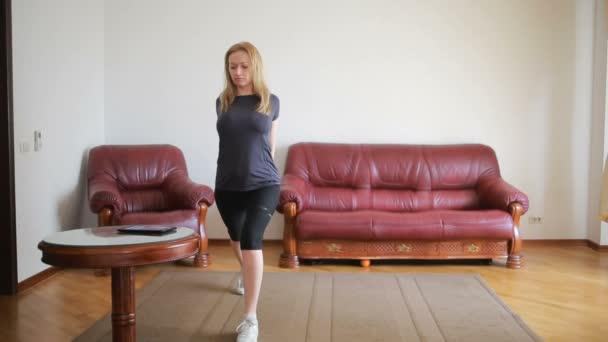 Une femme au foyer fait des exercices de fitness pour la première fois, en regardant la tablette et la télévision, c'est difficile et inconnu, elle est fatiguée . — Video