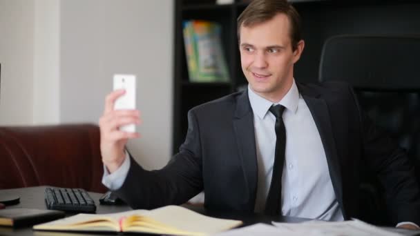 Attractive business man talking on the phone doing selfie at the office — Stock Video