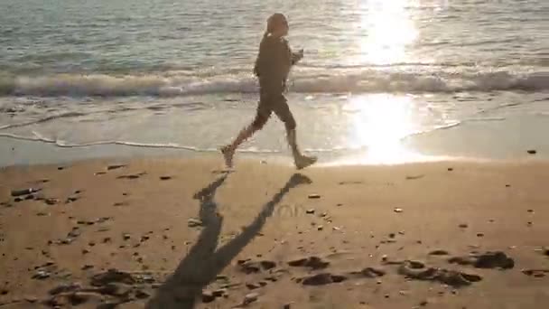 ผู้หญิงสวมรองเท้าผ้าใบวิ่งไปตามชายฝั่งทะเล หนีไปยังทะเล — วีดีโอสต็อก