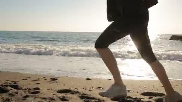 Damskie nogi w buty do biegania biegnącej wzdłuż brzegu morza, oceanu. Prowadzony przez morze — Wideo stockowe