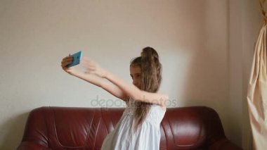 Küçük kız selfie smartphone cep telefonu ile evde kanepede yapıyor