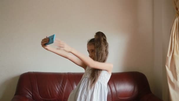 スマート フォンを自宅のソファの上に selfie をしている少女 — ストック動画