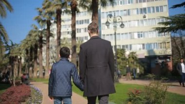 Baba ve oğul şehirde park sokak boyunca yürüyüş