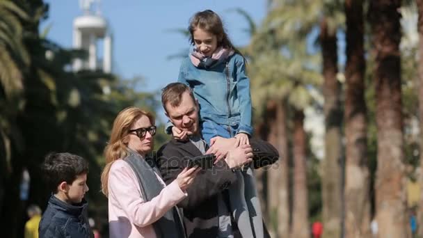 Feliz familia sonriendo. La gente es fotografiada en un teléfono móvil paseando por la calle — Vídeos de Stock