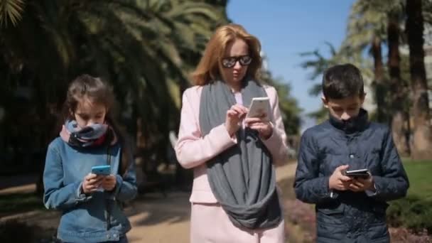 Mujer con hijos. Mamá y los niños están caminando por el callejón, todo el mundo está ocupado con su teléfono — Vídeos de Stock