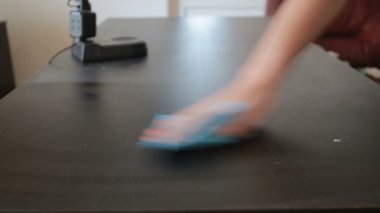 El mavi bir bez tutar ve onun toz masadan mendil