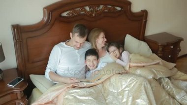 Evde sesli kitap okumayı yatakta mutlu aile