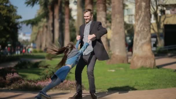 Feliz hija y padre están caminando en el parque, padre está girando las manos de sus hijas — Vídeo de stock