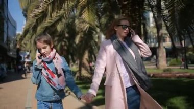 Çocuklu bir kadın. Anne ve kızı sokakta yürüyor, herkes onların telefon ile meşgul