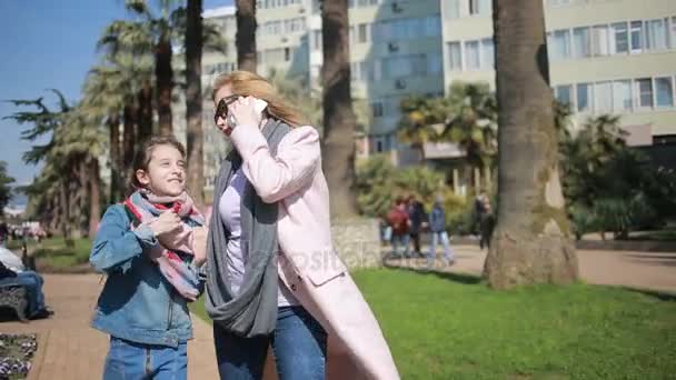 Una mujer con un hijo, una madre hablando por teléfono, caminando por el callejón, ignorando el mensaje de su hija, la hija requiere la atención de las madres — Vídeos de Stock