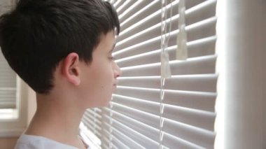 Çocuk sokakta kör pencereden görünüyor