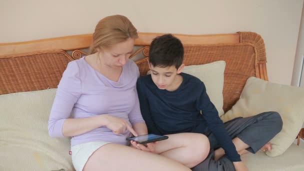 Mãe e seu filho adolescente falam bem, olhe para o tablet toque na tela sensível ao toque — Vídeo de Stock