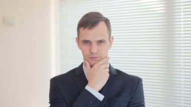 Yöneticisi kameraya ofis perdeleri arka plan üzerine düşünceli görünüyor. Kopya alanı.
