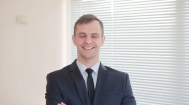 Fotoğraf makinesi üzerinde bir başparmak bir jesti gösterilmesini kör bir arka plan üzerine bir ofiste duran genç işadamı