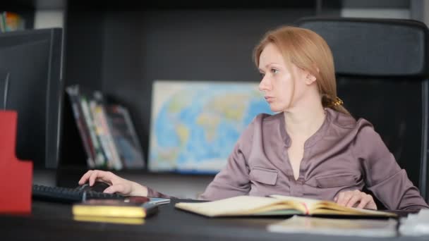 Atractiva mujer de negocios que trabaja con una computadora y documentos en la oficina — Vídeos de Stock