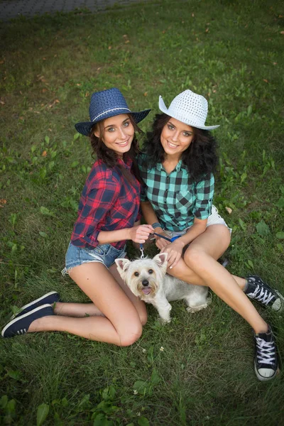 Dua gadis berjalan dengan anjingnya. topi koboi dan kemeja kotak-kotak — Stok Foto