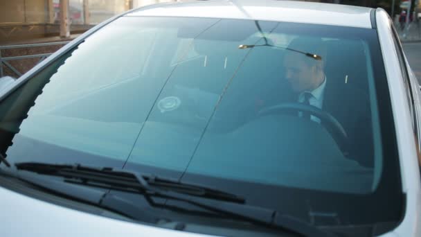 Businessman eating fast food sitting at the wheel of a car — Stock Video