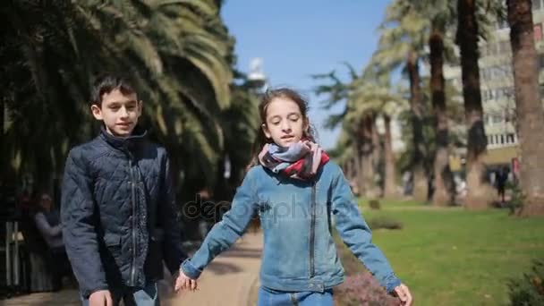 Dois filhos, irmão e irmã. gêmeos andando no parque no beco — Vídeo de Stock