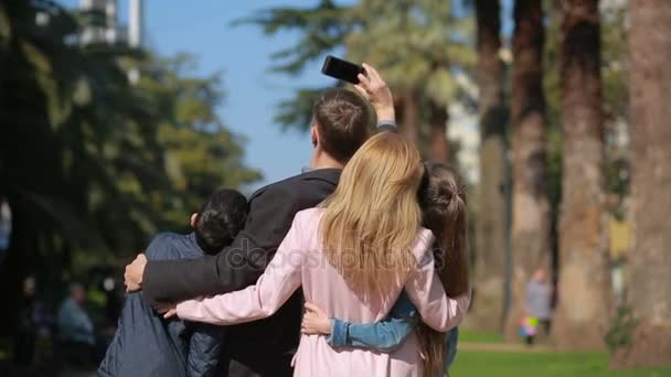Glückliche Familie lächelnd. Menschen werden mit dem Handy beim Spazierengehen auf der Straße fotografiert — Stockvideo