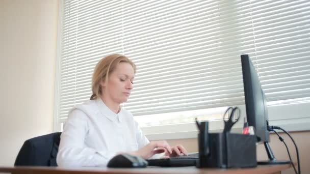 Привлекательная деловая женщина, работающая с компьютером и документами в офисе — стоковое видео