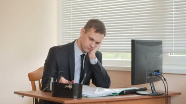 Ofis Yöneticisi çalışmalarını yorgun masada oturur