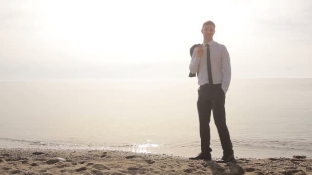 Affärsman promenader längs stranden i en kostym. beundrar den vackra stranden — Stockvideo