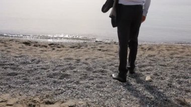 İşadamı elbiseli bir plaj boyunca elini kolunu sallaya dönüyor. güzel plaj hayran