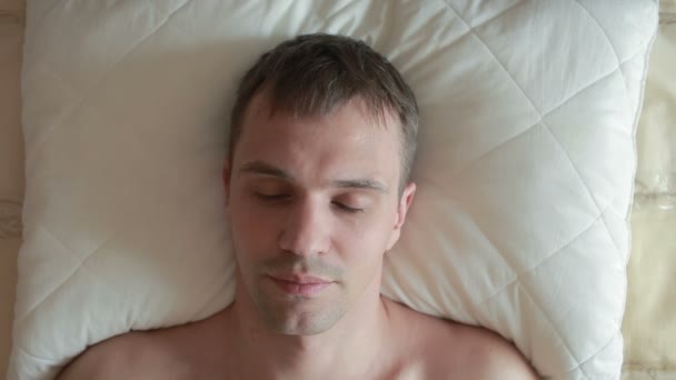 Um homem dorme na cama com um sono inquieto. Abre os olhos, olha para a câmara e grita de medo. Close-up. Vista de cima — Vídeo de Stock