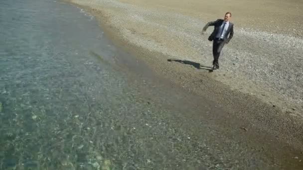 Uomo d'affari vestito. Danze Ammira la bellissima spiaggia . — Video Stock
