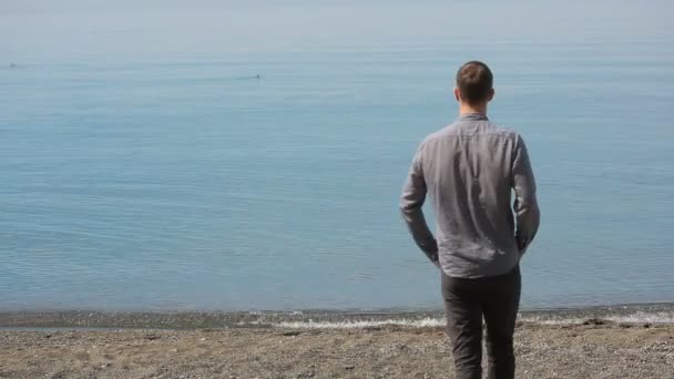 Uomo d'affari passeggia lungo la spiaggia con un completo. ammira la bellissima spiaggia — Video Stock