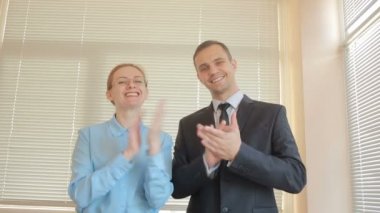 İki işadamı erkek ve kadın panjurlar bir pencere zemin üzerine bir ofiste alkışlar. Alkış