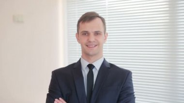 Fotoğraf makinesi üzerinde bir başparmak bir jesti gösterilmesini kör bir arka plan üzerine bir ofiste duran genç işadamı