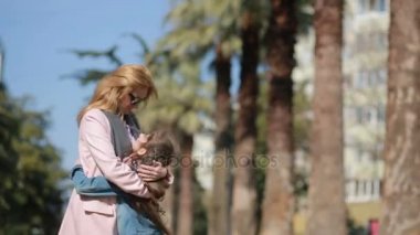 Bir kadın palmiye ağaçları ile bir cadde boyunca strolling el tarafından İkizler tutarak bir anne ile çocuk,