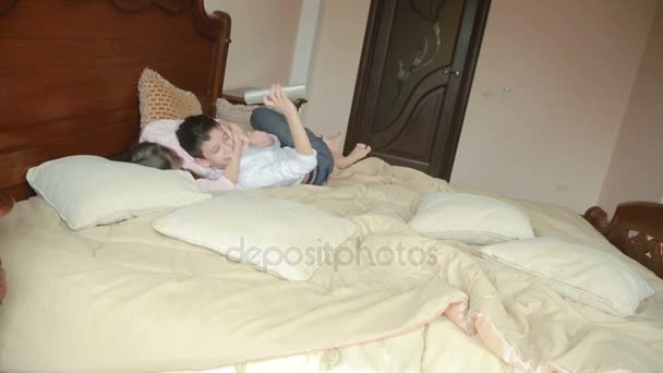 Brother and sister fights and pushes each other at home in the parents bedroom. fighting for the phone — Stock Video