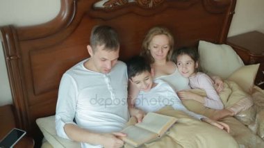 Evde sesli kitap okumayı yatakta mutlu aile