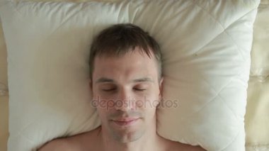 Adam yatakta yatıyor ve keskin gözlerini açar, içine belgili tanımlık fotoğraf makinesi ve gülümsüyor görünüyor. Yakın çekim. Yukarıdan görüntülemek