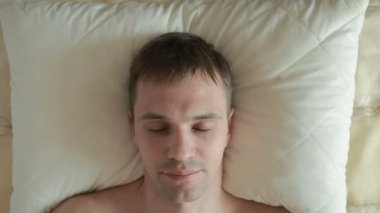 Adam yatakta yatıyor ve keskin gözlerini açar, içine belgili tanımlık fotoğraf makinesi ve gülümsüyor görünüyor. Yakın çekim. Yukarıdan görüntülemek